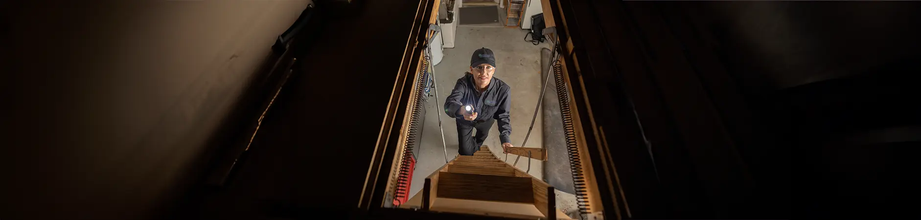 Exterminator on the attic stairs with a flashlight | Allied Termite & Pest Control serving Memphis, TN